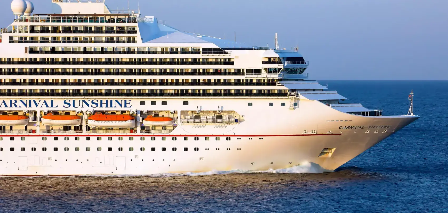 A large cruise ship, the Carnival Sunshine, sailing on a clear blue ocean