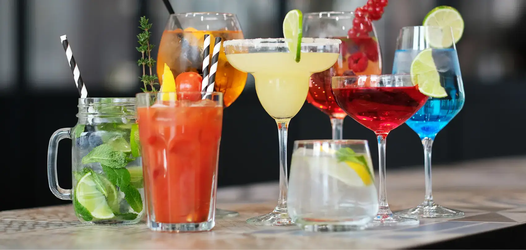 A variety of colorful cocktails on a bar, including a margarita