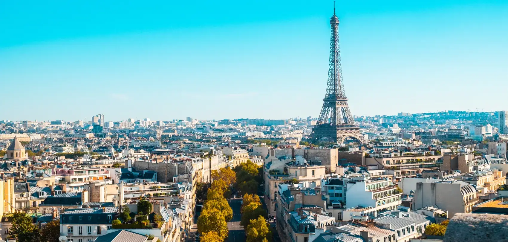 A cityscape of Paris in the sunlight with a blue sky in the background